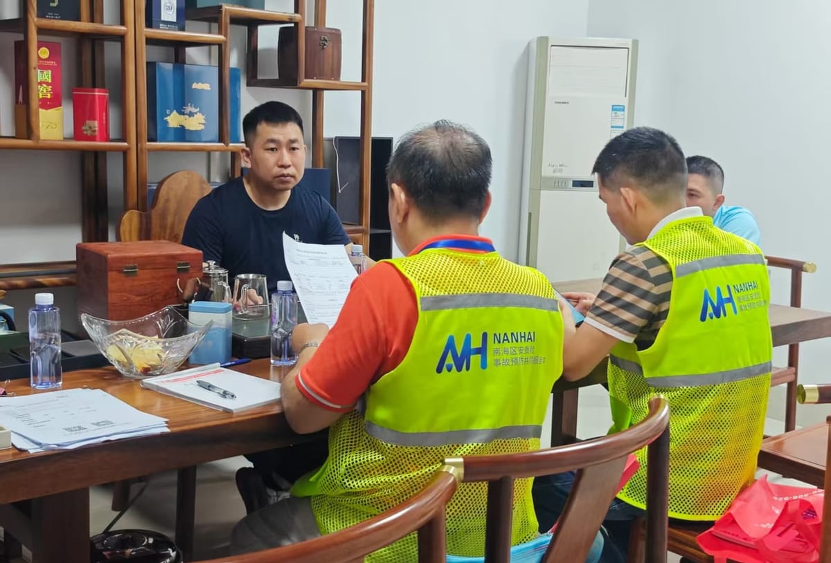 Machine safety walkthrough discussion between visiting engineers and plant staff beside production equipment in a metal fabrication workshop
