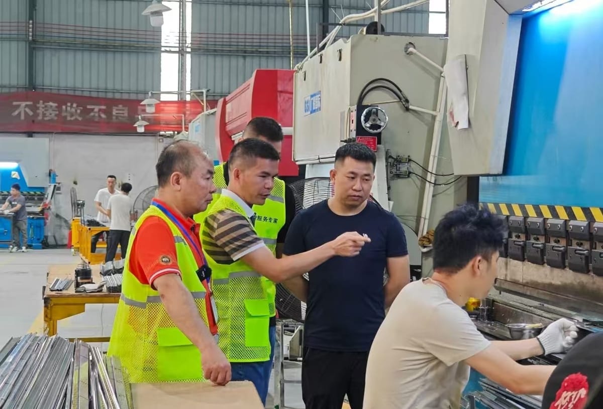 DAIDISIKE safety engineers in high-visibility vests carrying out an on-site hazard assessment at a hydraulic press brake in a sheet-metal fabrication plant